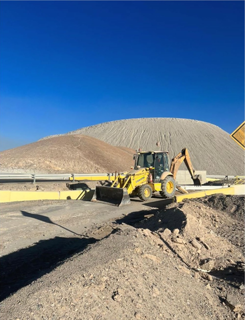 Retroexcavadora realizando trabajos de excavación y conformación de plataforma operativa.